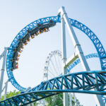 Roller coaster Ride against blue sky. Roller coaster in the amusement park. Cheerful entertainments in park of attractions Roller coaster Ride against blue sky. Roller coaster in the amusement park. Cheerful entertainments in park of attractions