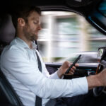 A middle aged caucasian man distracted driving while using a mobile device. A middle aged caucasian man distracted driving while using a mobile device.