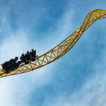 Ride roller coaster in motion in amusement park on blue sky background. Ride roller coaster in motion in amusement park on blue sky background.