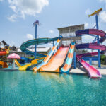 water park slide with swimming pool at amusement park - colored plastic water slides with pool in outdoor aqua park water park slide with swimming pool at amusement park - colored plastic water slides with pool in outdoor aqua park